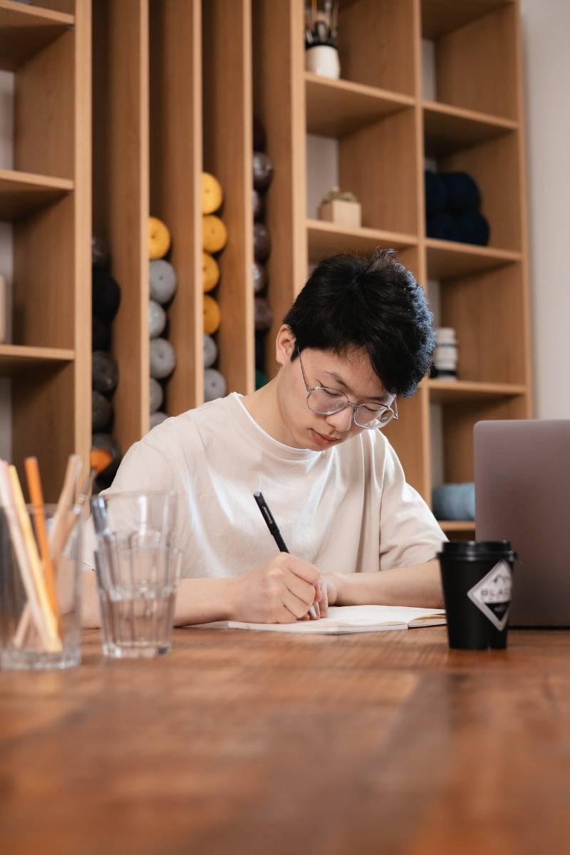 a young man writing on a table